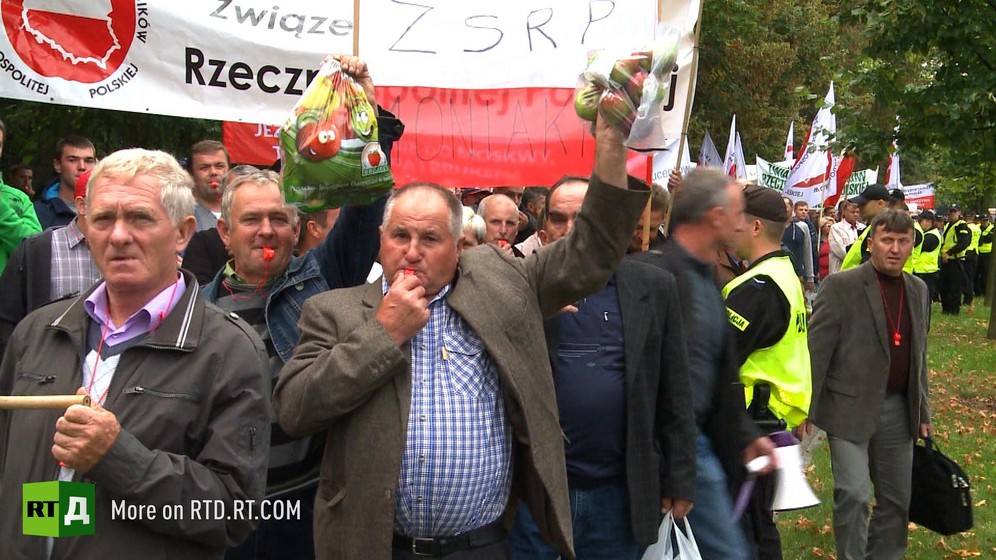 Polish farmers hold up bags of apples and blow whistles, others hold banners, during a demonstration. Still taken from RTD documentary Apples of Discord.