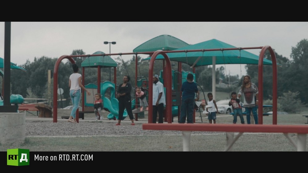 Playground with African American families playing on swings. Still taken from RTD documentary, Black Lives 10: Trap.