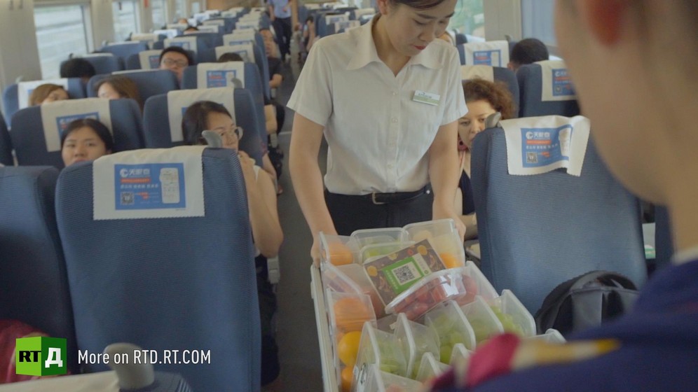 In a Chinese high speed train, a female attendant guides a trolley with food.  Still taken from RTD documentary Chinese Speed  in the This is China series.
