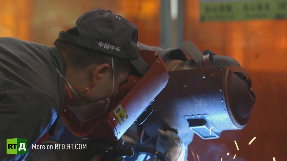 At a Chinese high speed train manufacturing plant, two welders wearing protective helmets are producing sparks.  Still taken from RTD documentary Chinese Speed  in the This is China series.