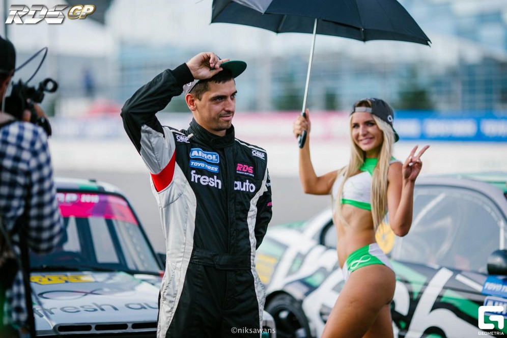 A glamorous grid girl holds an umbrella over leading contender Vorobiev, who is lost in thought.