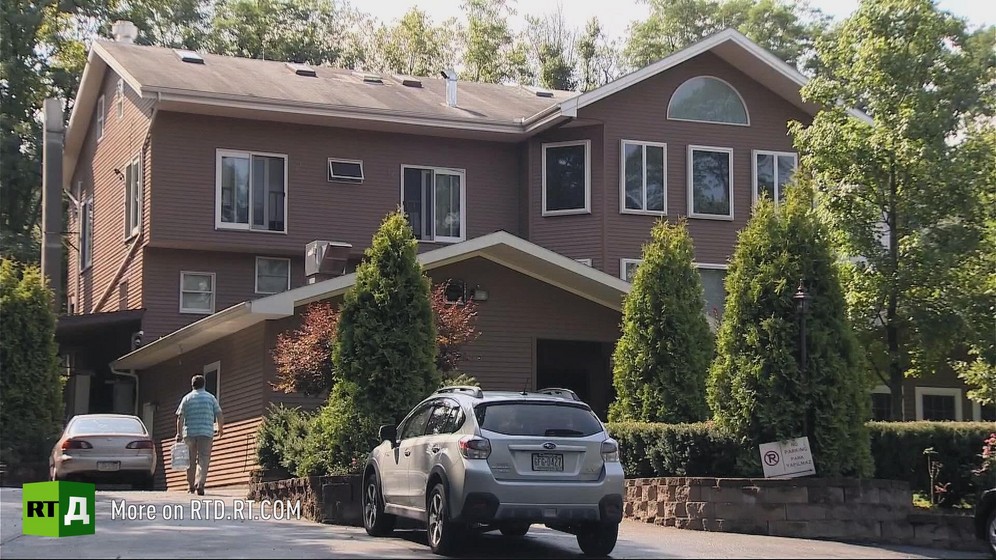 View of the house where Fethullah Gulen lives in Pensylvania, surrounded by trees, with two cars in the drive and one man in the background. Still taken from RTD's documentary series on Fethullah Gulen, The Gulen Mystery, Episode 4: Gulen's Turkish Charter Schools.