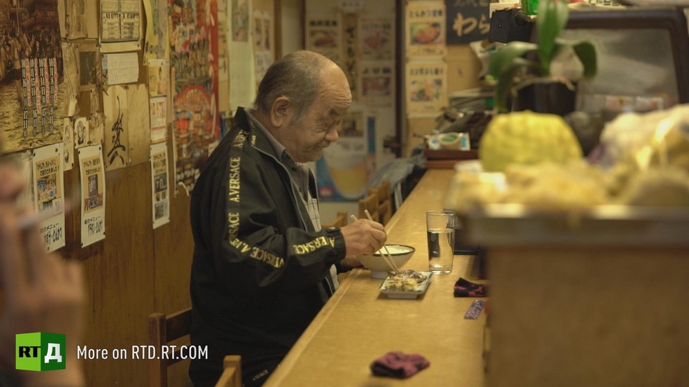 A lonely Japanese old man eating in a restaurant. A screenshot from Dying Alone documentary