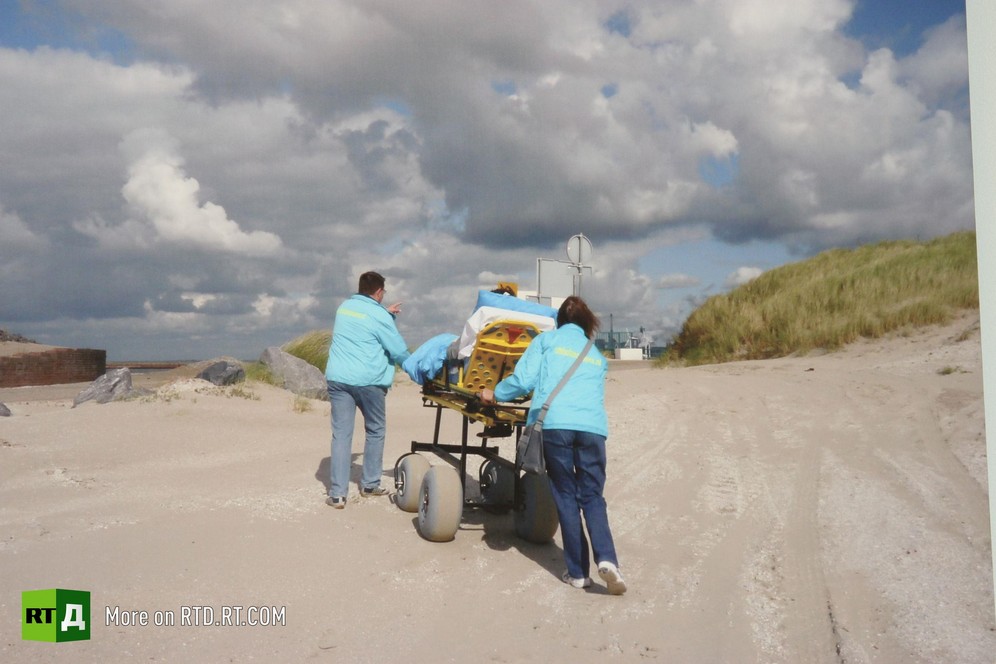 A terminally ill patient is being led along the beach in an ambulance stretcher by two volunteers from the Ambulance Wish Foundation in the Netherlands. Picture taken during filming of RTD documentary Last Wishes.