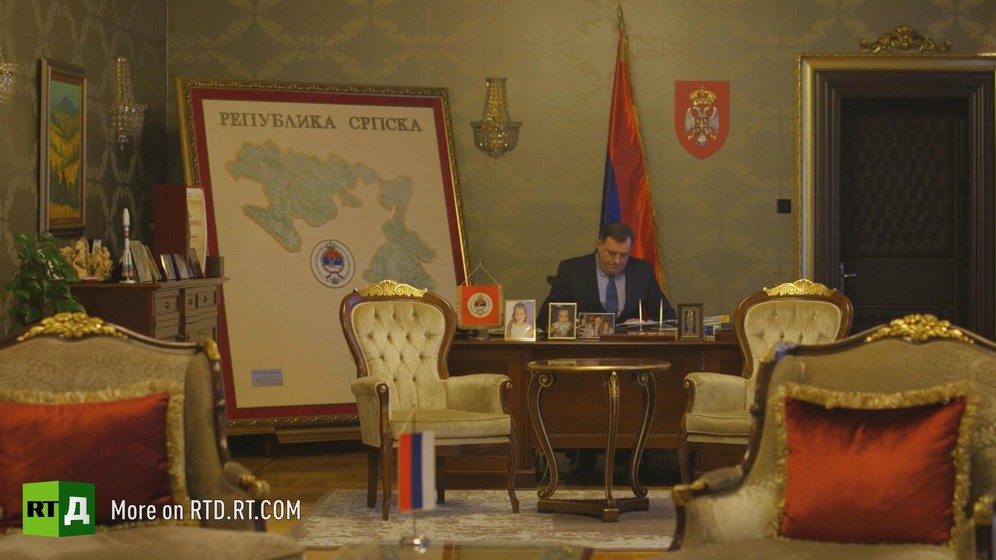 Former Republika Srpska President Miloslav Dodic, currently chairman of the Presidency of Bosnia-Herzegovina, sits at his desk in front of a flag and a large map of Republika Srpska, with velvet upholstered armchairs in the foreground. Still taken from RTD documentary Republika Srpska.