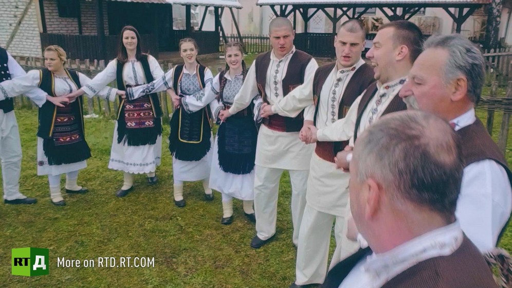 Group of young women and men from Republika Srpska in traditional costume holding hands during a dance. Still taken from RTD documentary Republika Srpska.