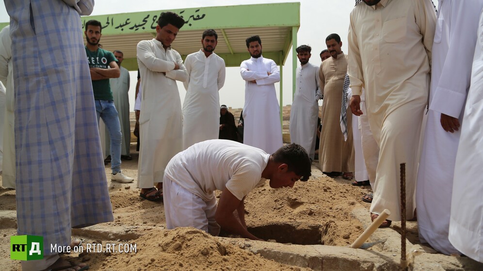 In Wadi Al-Salam cemetery in Najaf, Iraq, surrounded by onlookers, a young gravedigger gets to work. Still taken while filming the RTD documentary Sons of the Graveyard.