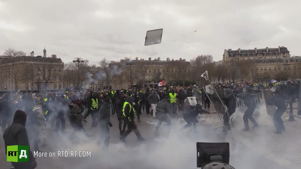 A barrier thrown by protesters is flying mid air at the Arc de Triomphe in Paris during a Yellow Vest protest. 