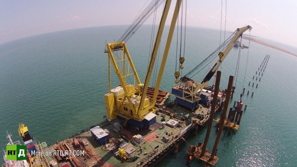 Building of Crimea Bridge, aerial view of yellow crane and sea. Still taken from RTD documentary The Bridge.