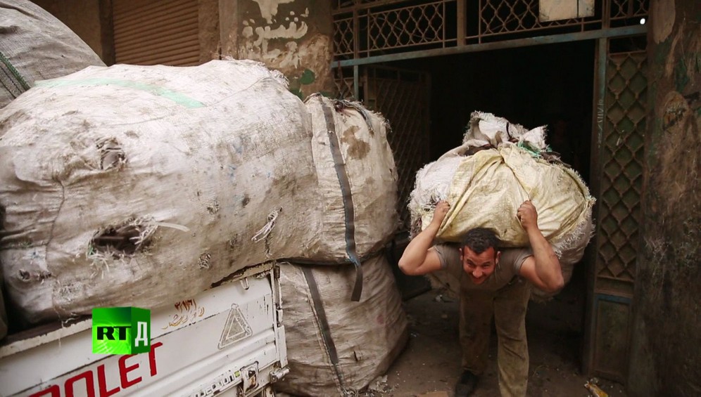 Zabbaleen Cairo rubbish collector carrying a huge bail of trash in Garbage City