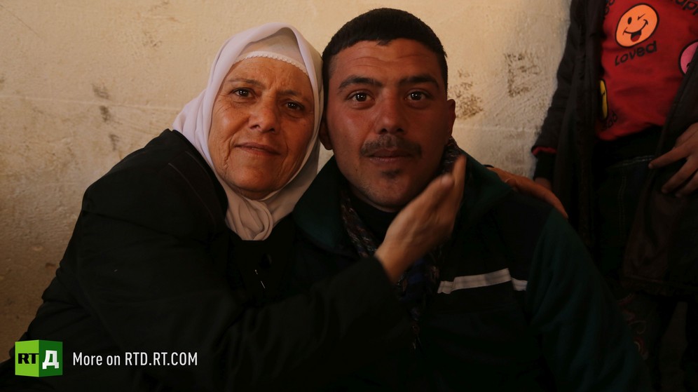 Syrian mother in traditional dress wearing a headscarf is holding her adult soldier son and stroking his face, at the barracks of the Syrian Army unit for amnestied fighters. Taken while filming RTD documentary about Syrian amnestied fighters Amnesty in Wartime.