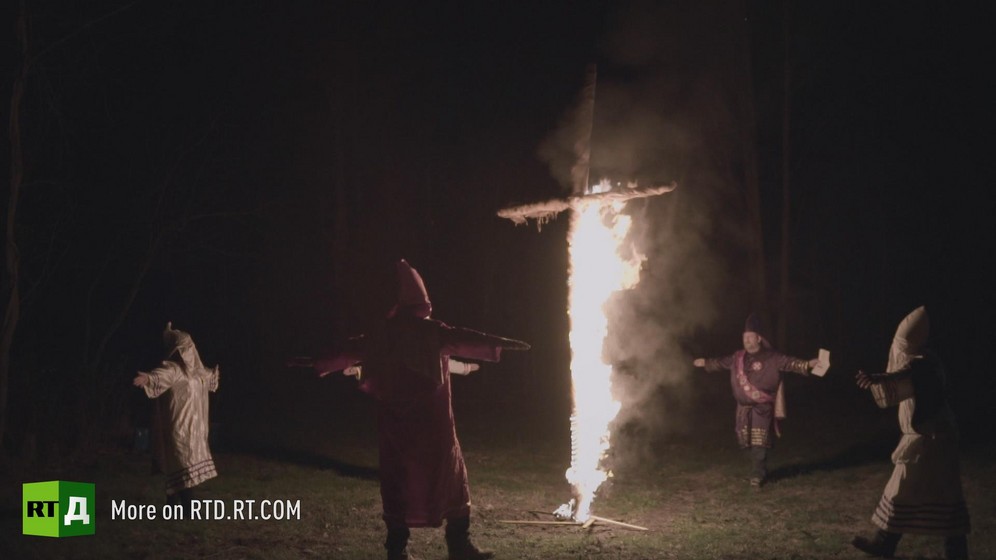 At nighttime, hooded Klansmen stand around a burning cross. Still taken from RTD documentary Black Lives 8: Deadlock.