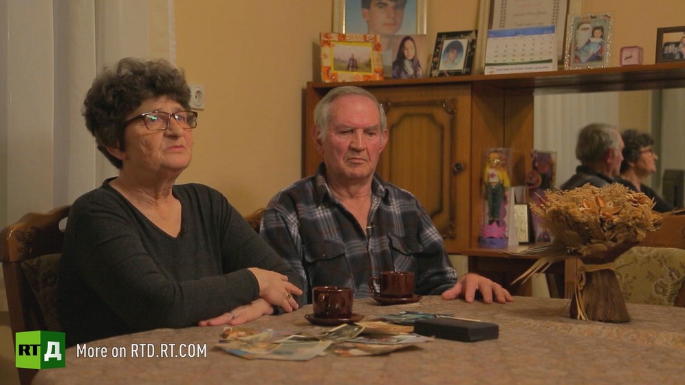 Elderly Bosnian Serb couple sitting at a table with family photographs spread out in front of them. Still taken from RTD documentary Republika Srpska.