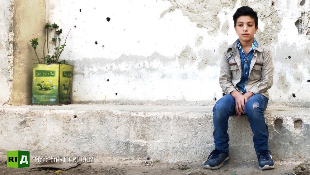 Young teenage boy sitting on a wall in Duma, Syria, looking sad. He became a child soldier aged eleven, and was forced to dig tunnels for Jaish Al Islam rebels. Still taken from RTD documentary about child fighters Where Childhood Died.