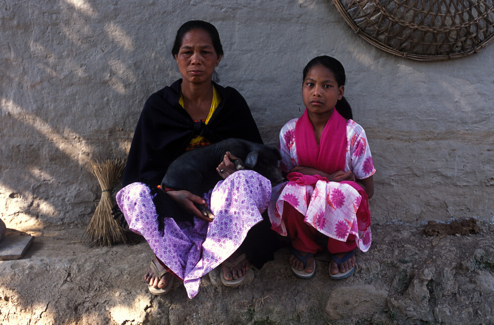 Rama Chandari, a former Kamlari (bonded labourer), sits with her mother - who holds the pig traded for her release