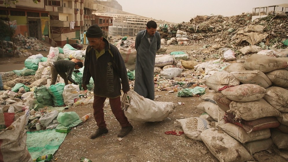 Zabbaleen Cairo Garbage Collectors' Union leader Shehata al-Moqadis watches a rubbish collector sorting through a pile of trash outside in Garbage City