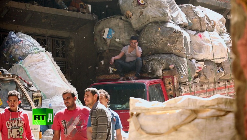 Garbage truck overloaded with huge bails of trash in Garbage City by the Zabbaleen Cairo's legendary rubbish collectors with man on top of the truck
