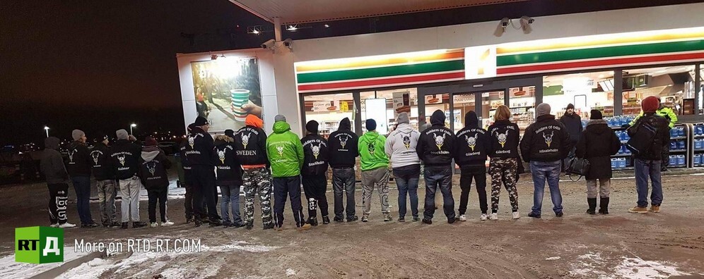 Volunteers belonging to the Sons of Odin in Sweden stand with their back turned in a line at  night. Still taken from RTD documentary Testing Tolerance.